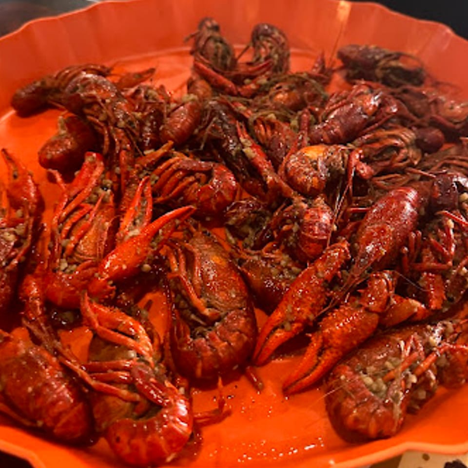 A vibrant orange platter overflowing with a generous serving of seasoned, cooked crawfish.