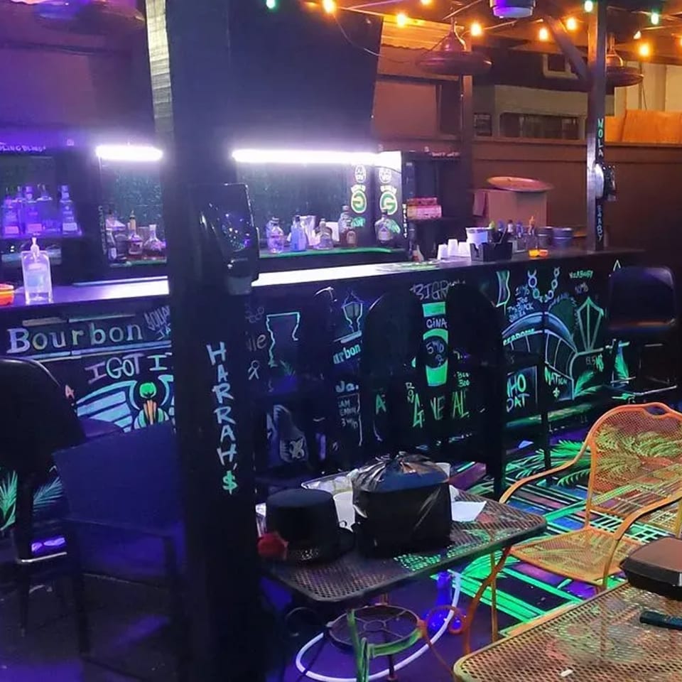 The Bourbon Square Jazz Bar's interior with a glowing bar, neon signs, and outdoor-style seating.