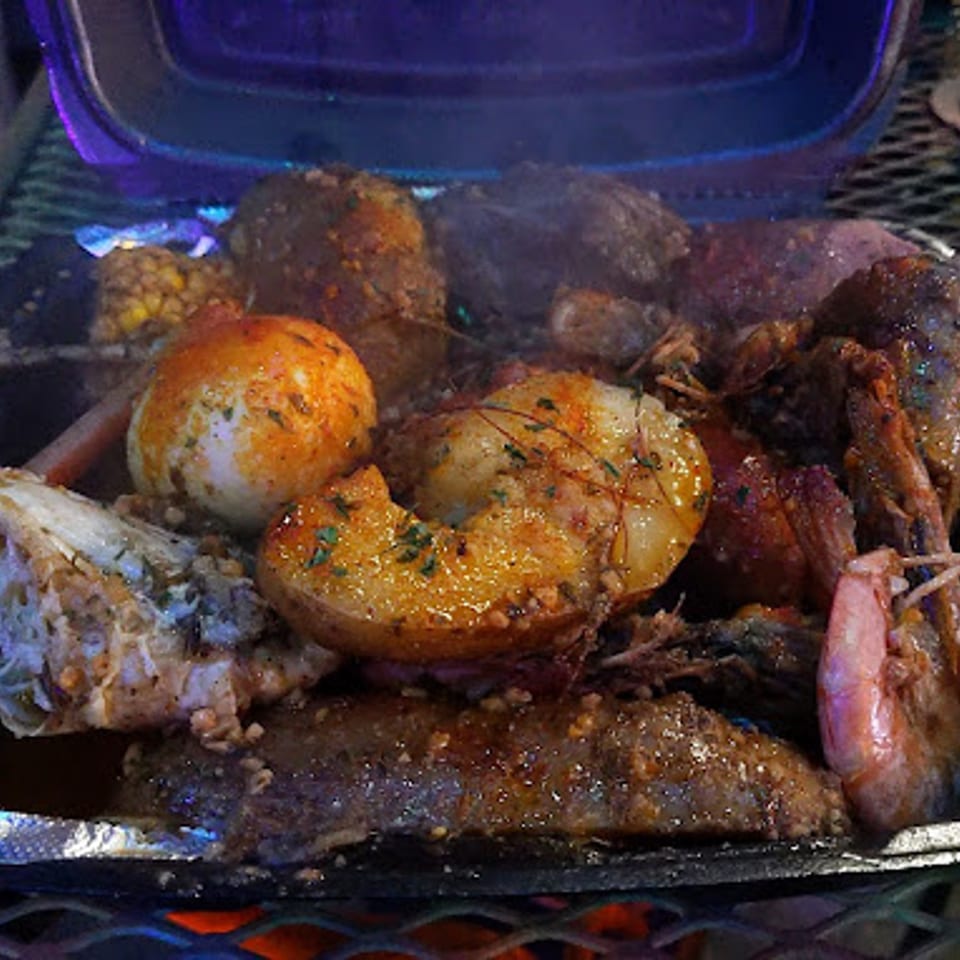 A close-up of a seafood boil with shrimp, potatoes, and corn on the cob.
