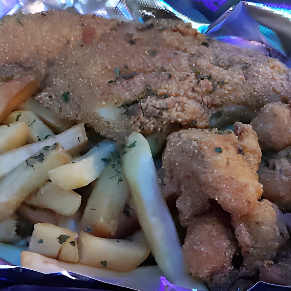Crispy fried fish and golden french fries with seasoning, served in a foil container.